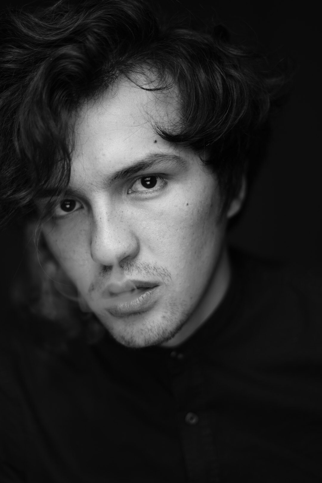 Studio portrait of a young man with tousled hair looking off camera