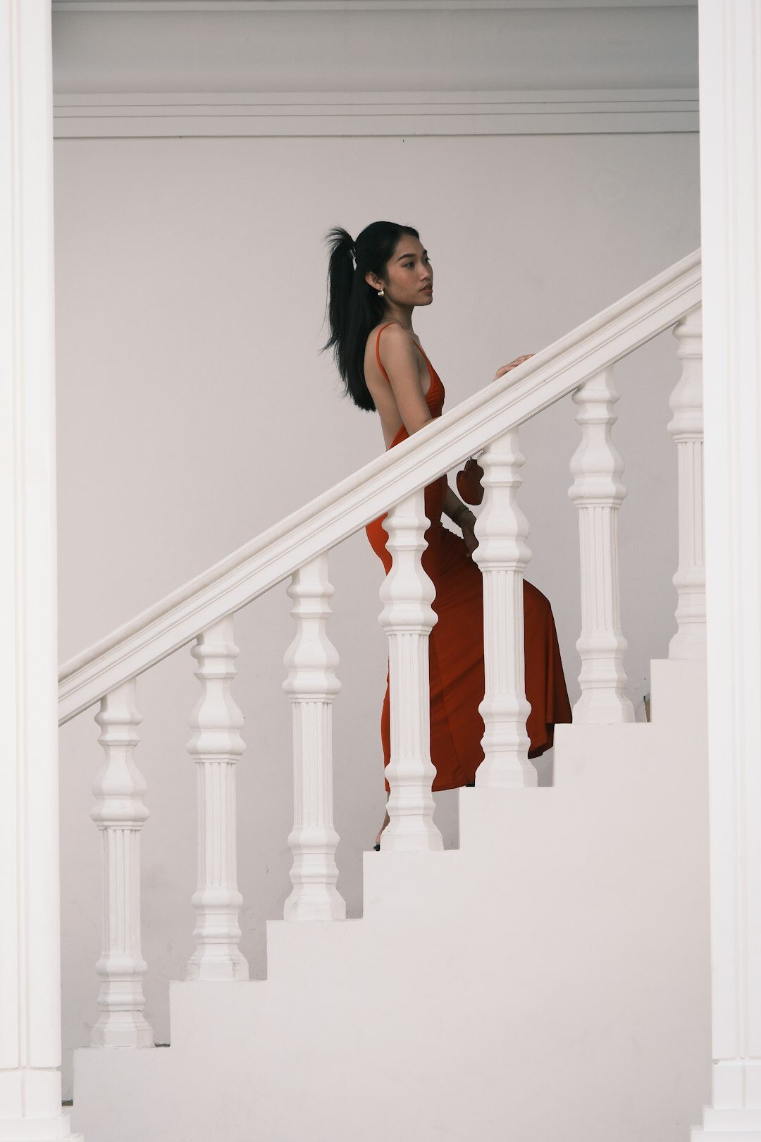 Vertical fashion editorial shot of a woman in a flowing gown on a staircase